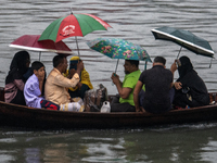 Passengers hold umbrellas as they cross the Buriganga River during rain in Dhaka, Bangladesh, on October 24, 2024. Light rain and wind from...