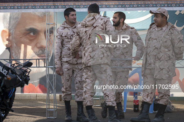 Islamic Revolutionary Guard Corps (IRGC) military personnel stand together next to a banner featuring a portrait of the killed Hamas Leader,...