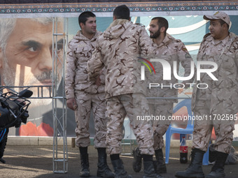 Islamic Revolutionary Guard Corps (IRGC) military personnel stand together next to a banner featuring a portrait of the killed Hamas Leader,...