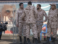 Islamic Revolutionary Guard Corps (IRGC) military personnel stand together next to a banner featuring a portrait of the killed Hamas Leader,...