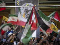 Iranian people wave Palestinian and Iranian flags in front of a banner featuring a portrait of the killed Hamas Leader, Yahya Sinwar, during...