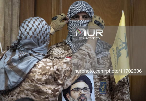 An Islamic Revolutionary Guard Corps (IRGC) military personnel, wearing a Palestinian scarf and a uniform symbolizing Hamas warriors, holds...