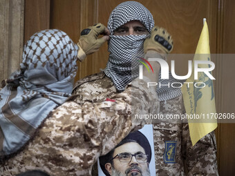 An Islamic Revolutionary Guard Corps (IRGC) military personnel, wearing a Palestinian scarf and a uniform symbolizing Hamas warriors, holds...