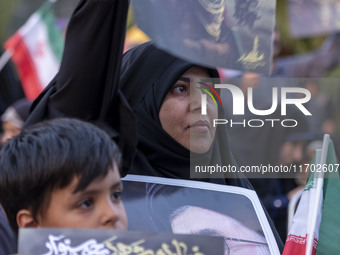 An Iranian schoolboy and a woman hold portraits of the killed Hamas Leader, Yahya Sinwar, while they take part in a ceremony commemorating S...