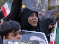 An Iranian schoolboy and a woman hold portraits of the killed Hamas Leader, Yahya Sinwar, while they take part in a ceremony commemorating S...