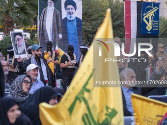 Islamic Revolutionary Guard Corps (IRGC) personnel, wearing masks and uniforms symbolizing Hamas warriors, stand under portraits of Iran's S...