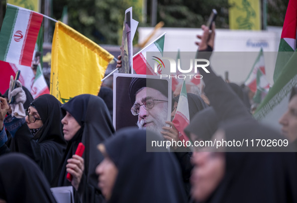 A veiled Iranian woman holds up a portrait of Iran's Supreme Leader, Ayatollah Ali Khamenei, while taking part in a ceremony commemorating t...