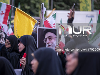 A veiled Iranian woman holds up a portrait of Iran's Supreme Leader, Ayatollah Ali Khamenei, while taking part in a ceremony commemorating t...