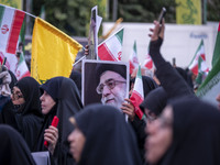 A veiled Iranian woman holds up a portrait of Iran's Supreme Leader, Ayatollah Ali Khamenei, while taking part in a ceremony commemorating t...