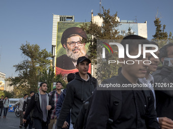 Young Iranian men walk under a giant banner featuring a portrait of Lebanon's Hezbollah Secretary General, Hashem Safieddine, who is killed...