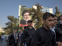 Young Iranian men walk under a giant banner featuring a portrait of Lebanon's Hezbollah Secretary General, Hashem Safieddine, who is killed...