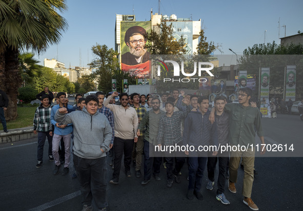 Young Iranian men shout anti-U.S. and anti-Israeli slogans while walking under a portrait of Lebanon's Hezbollah Secretary General, Hashem S...