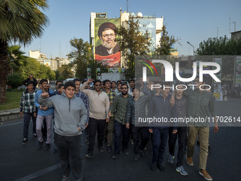 Young Iranian men shout anti-U.S. and anti-Israeli slogans while walking under a portrait of Lebanon's Hezbollah Secretary General, Hashem S...