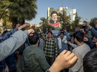 Young Iranian men shout anti-U.S. and anti-Israeli slogans under a portrait of Lebanon's Hezbollah Secretary General, Hashem Safieddine, who...