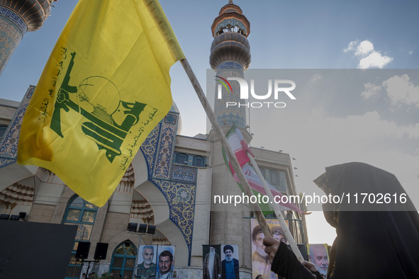 A veiled Iranian woman waves a flag of Lebanon's Hezbollah and an Iranian flag while taking part in a ceremony commemorating the killed Hama...