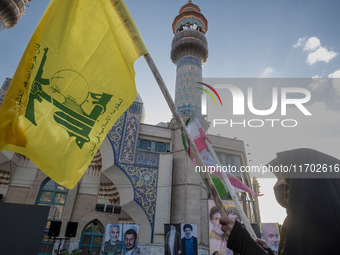 A veiled Iranian woman waves a flag of Lebanon's Hezbollah and an Iranian flag while taking part in a ceremony commemorating the killed Hama...