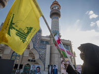 A veiled Iranian woman waves a flag of Lebanon's Hezbollah and an Iranian flag while taking part in a ceremony commemorating the killed Hama...