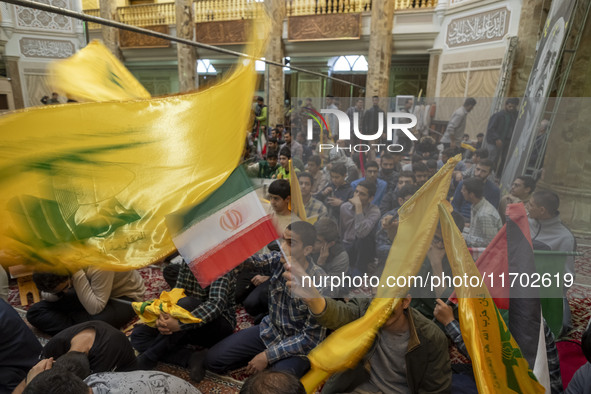 Iranian men wave an Iranian flag and flags of Lebanon's Hezbollah while taking part in a ceremony commemorating the killed Hamas Leader, Yah...