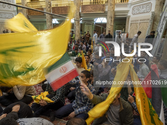 Iranian men wave an Iranian flag and flags of Lebanon's Hezbollah while taking part in a ceremony commemorating the killed Hamas Leader, Yah...