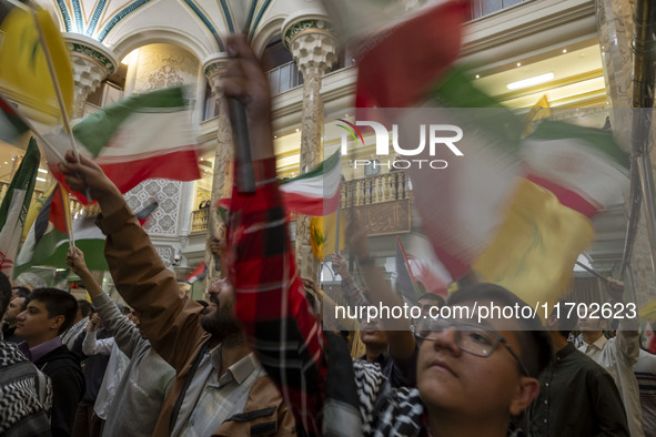 Iranian men wave an Iranian flag and flags of Lebanon's Hezbollah while taking part in a ceremony commemorating the killed Hamas Leader, Yah...