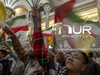 Iranian men wave an Iranian flag and flags of Lebanon's Hezbollah while taking part in a ceremony commemorating the killed Hamas Leader, Yah...