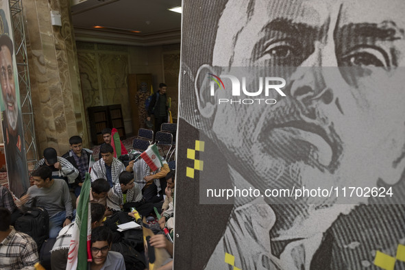 Young men hold Iranian flags and sit next to a banner featuring a portrait of the killed Hamas Leader, Yahya Sinwar, while taking part in a...