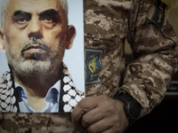 An Islamic Revolutionary Guard Corps (IRGC) military personnel holds a portrait of the killed Hamas Leader, Yahya Sinwar, while taking part...