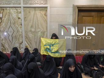 A veiled Iranian woman holds a flag of Lebanon's Hezbollah while participating in a ceremony commemorating the killed Hamas leader, Yahya Si...