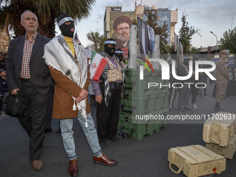 A group of Iranian men, wearing masks and flak jackets, symbolizes Hamas warriors and stands next to two tank bullet pumices during a ceremo...