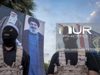 Two Islamic Revolutionary Guard Corps (IRGC) personnel, wearing masks and flak jackets, symbolize Hamas warriors and stand under the portrai...