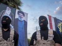 Two Islamic Revolutionary Guard Corps (IRGC) personnel, wearing masks and flak jackets, symbolize Hamas warriors and stand under the portrai...