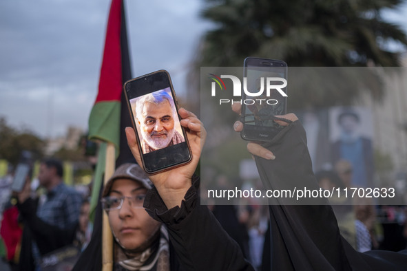 Two veiled women hold up their cellphones featuring portraits of the former commander of the Islamic Revolutionary Guard Corps' (IRGC) Quds...