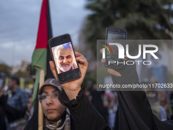 Two veiled women hold up their cellphones featuring portraits of the former commander of the Islamic Revolutionary Guard Corps' (IRGC) Quds...