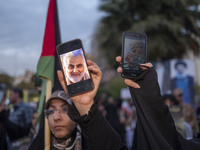 Two veiled women hold up their cellphones featuring portraits of the former commander of the Islamic Revolutionary Guard Corps' (IRGC) Quds...