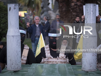 Two Islamic Revolutionary Guard Corps (IRGC) military personnel, wearing masks and flak jackets, symbolize Hamas warriors as they stand next...