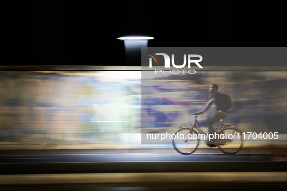 A motion-blurred shot shows an urban cyclist riding through a brightly lit bike lane in Foggia, Italy, on September 12, 2020. The dynamic ba...