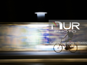 A motion-blurred shot shows an urban cyclist riding through a brightly lit bike lane in Foggia, Italy, on September 12, 2020. The dynamic ba...