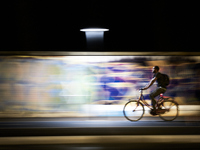 A motion-blurred shot shows an urban cyclist riding through a brightly lit bike lane in Foggia, Italy, on September 12, 2020. The dynamic ba...