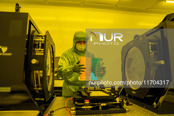 A researcher inspects grating surface patterns in the yellow light detection room of Anhui Zhongke Grating Technology Co., LTD in Hefei, Chi...