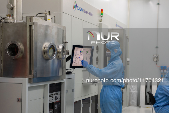 A researcher operates a grating ion beam etcher in the yellow light detection room at the research building of Anhui Zhongke Grating Technol...