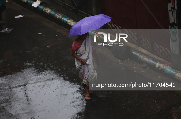 A woman walks on the street during rain due to Cyclone Dana in Kolkata, India, on October 25, 2024. The coastal districts of Odisha are batt...