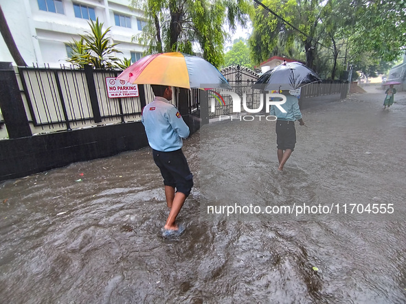 People walk on the waterlogged street during the heavy rain due to Cyclone Dana in Kolkata, India, on October 25, 2024. 