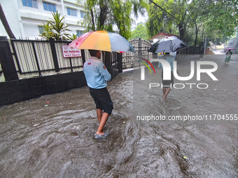 People walk on the waterlogged street during the heavy rain due to Cyclone Dana in Kolkata, India, on October 25, 2024. (