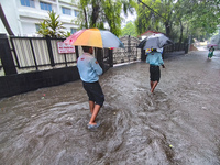 People walk on the waterlogged street during the heavy rain due to Cyclone Dana in Kolkata, India, on October 25, 2024. (