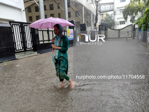 People walk on the waterlogged street during the heavy rain due to Cyclone Dana in Kolkata, India, on October 25, 2024. 