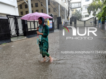 People walk on the waterlogged street during the heavy rain due to Cyclone Dana in Kolkata, India, on October 25, 2024. (