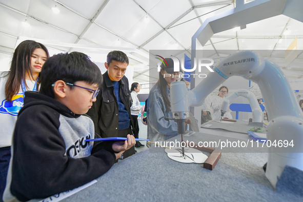 Citizens watch a performance of Chinese painting and calligraphy robot skills at the 7th World Sound Expo and IFLYtek Global 1024 Developer...