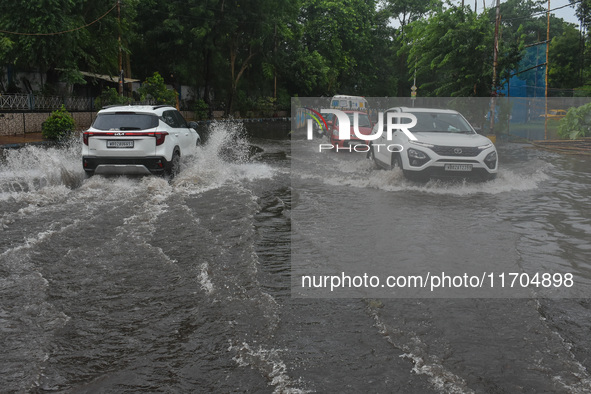 Motorists make their way through a flooded road after Cyclone Dana thrashes the city with heavy rain, as seen in Kolkata, India, on October...