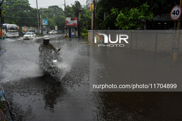 Motorists make their way through a flooded road after Cyclone Dana thrashes the city with heavy rain, as seen in Kolkata, India, on October...