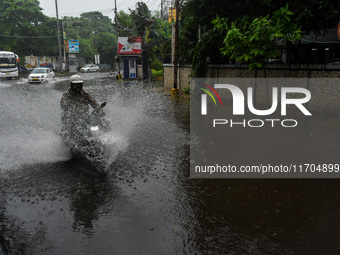 Motorists make their way through a flooded road after Cyclone Dana thrashes the city with heavy rain, as seen in Kolkata, India, on October...